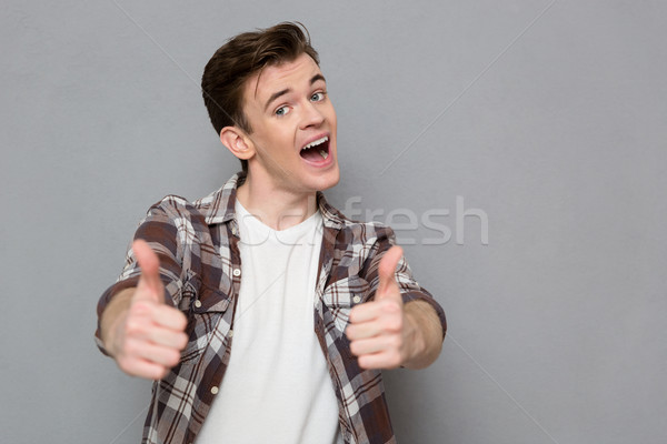 Joyful pleased happy young man giving thumbs up  Stock photo © deandrobot