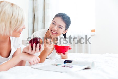Women relaxing on the bed with food and laptop computer Stock photo © deandrobot