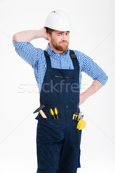 Thoughtful confused builder in helmet standing and scratching his head Stock photo © deandrobot