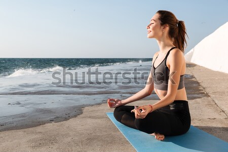 Woman meditating on the beach at sunset Stock photo © deandrobot