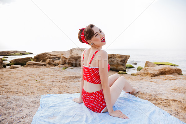 Happy cheerful pin up girl in red swimsuit winking Stock photo © deandrobot
