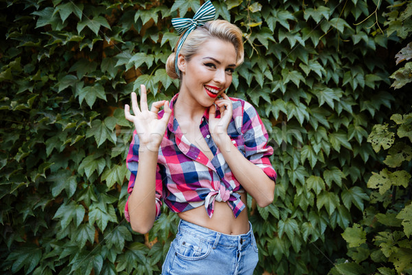 Smiling young woman showing ok gesture in the park Stock photo © deandrobot