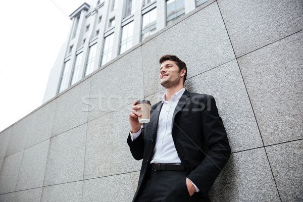 Cheerful young businesman drinking coffee outdoors Stock photo © deandrobot