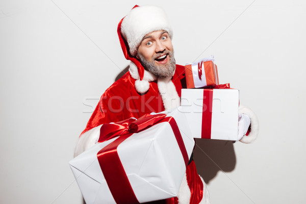 Happy man santa claus holding present boxes and laughing Stock photo © deandrobot