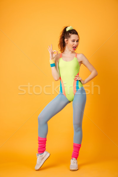 Smiling young fitness lady posing over yellow background Stock photo © deandrobot
