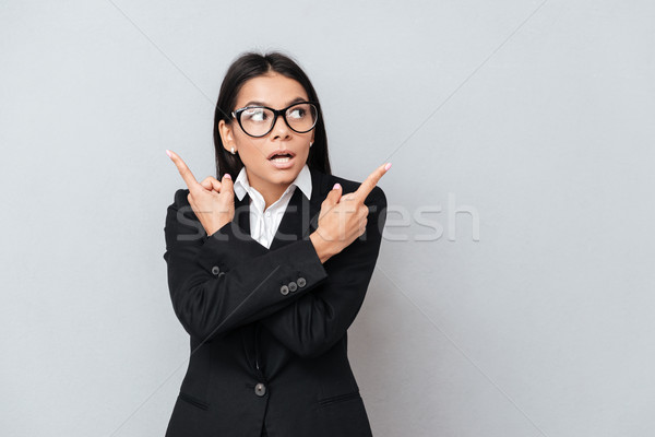 Young astonished business woman pointing sideways with two hands Stock photo © deandrobot