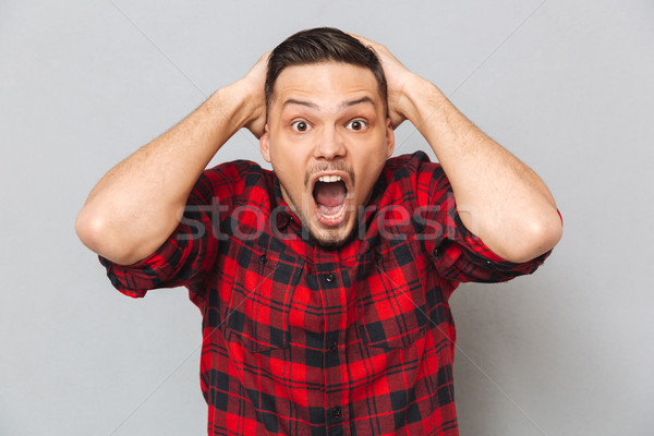 Screaming man holding head and looking at camera Stock photo © deandrobot
