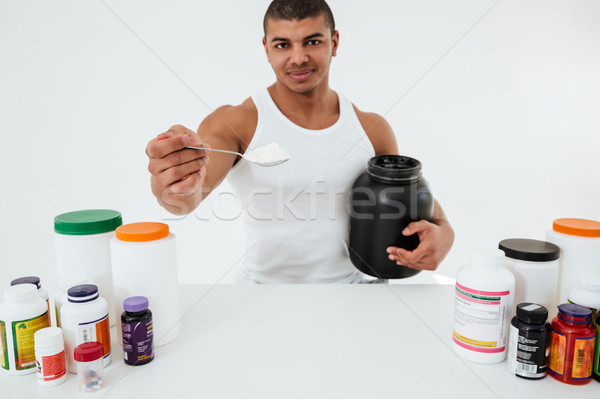 Sportsman standing over white background holding vitamins Stock photo © deandrobot