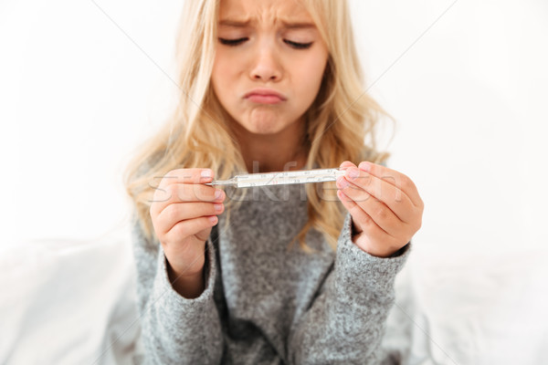 Close-up portrait of sick unhappy little girl holding thermomete Stock photo © deandrobot