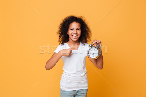 Portrait of a african girl pointing finger at alarm clock Stock photo © deandrobot