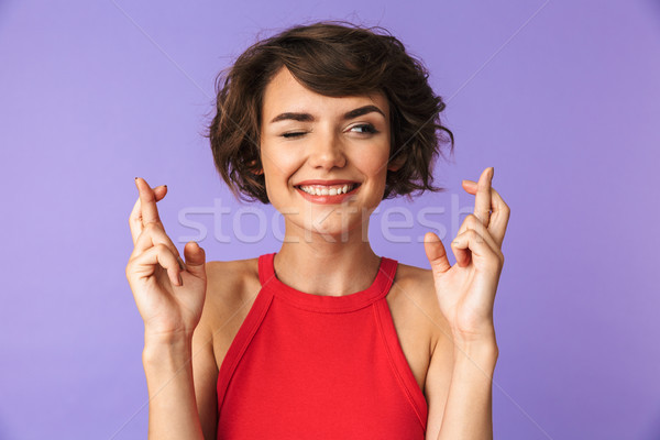Portrait of a smiling young girl showing fingers crossed Stock photo © deandrobot
