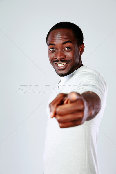Cheerful african man pointing at you over gray background Stock photo © deandrobot