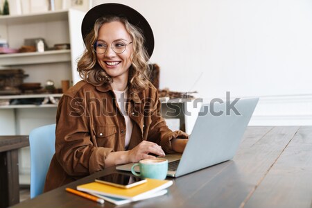 Young businesswoman sitting at desk and working. Smiling and looking back at camera Stock photo © deandrobot