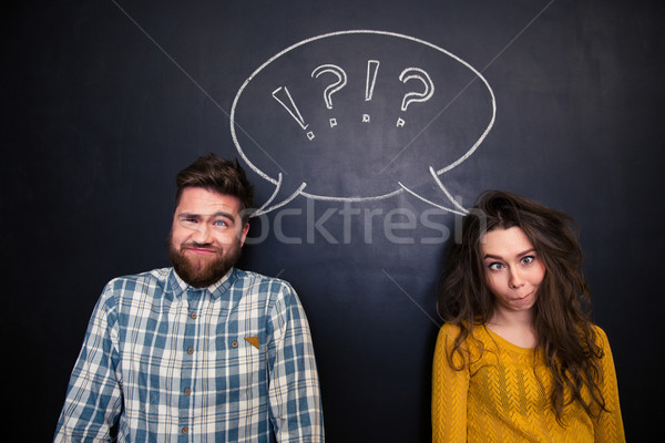 Ugly couple grimacing over chalkboard background Stock photo © deandrobot
