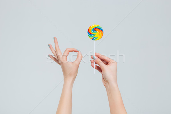 Stock photo: Female hands holding lollipop and showing ok sign with fingers