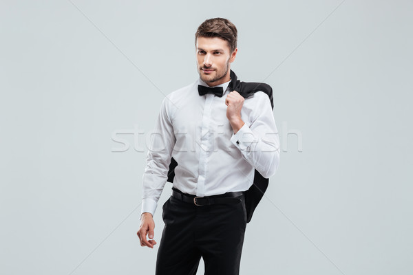 Handsome young man in tuxedo with bowtie holding his jacket Stock photo © deandrobot