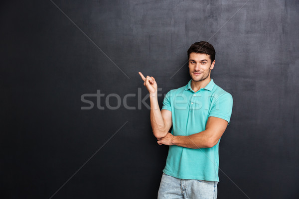 Człowiek niebieski tshirt stałego wskazując z dala Zdjęcia stock © deandrobot