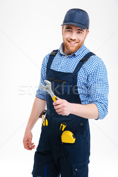 Cheerful bearded repairman standing and holding adjustable wrench Stock photo © deandrobot
