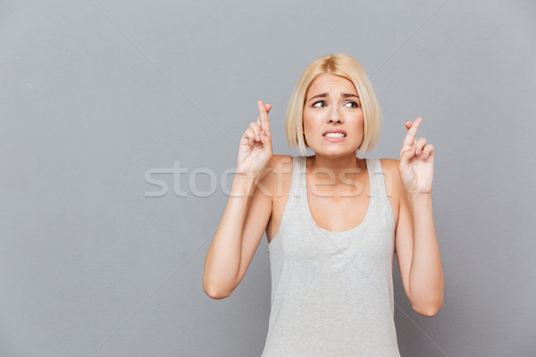 Tensed nervous young woman standing with fingers crossed Stock photo © deandrobot