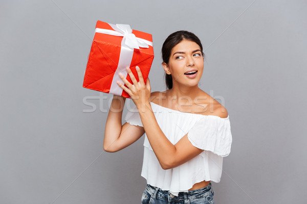 Cheerful young woman wonder what is inside present box Stock photo © deandrobot