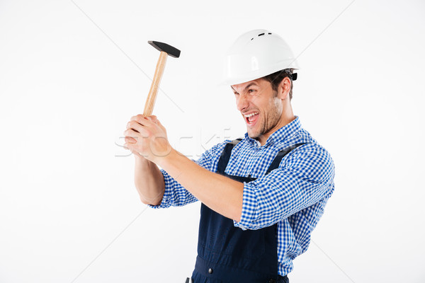 Funny young builder applying hummer to his head in helmet Stock photo © deandrobot