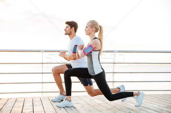 Sporty couple warming up before jogging at the beach Stock photo © deandrobot