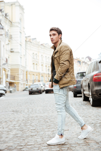 Young man walking on the street and looking aside. Stock photo © deandrobot