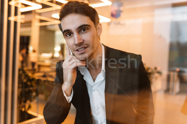 Smiling business man talking on phone behind the glass Stock photo © deandrobot