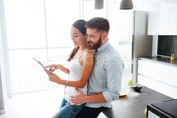 Man hugs woman with tablet from behind Stock photo © deandrobot