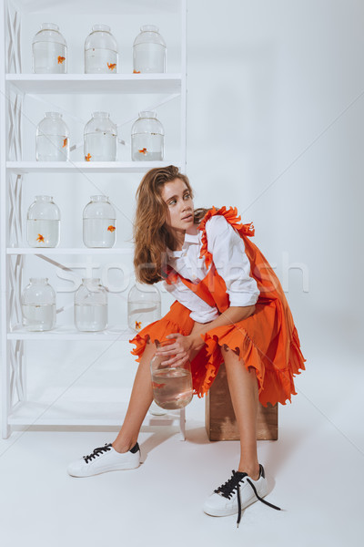 Woman with gold fish in jar sitting and looking back Stock photo © deandrobot