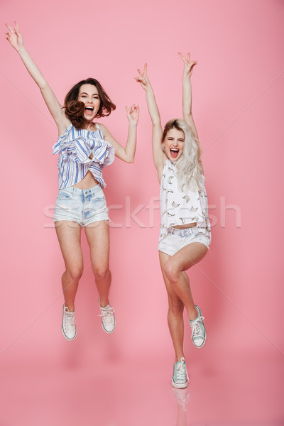 Full length of two happy excited women jumping and shouting Stock photo © deandrobot