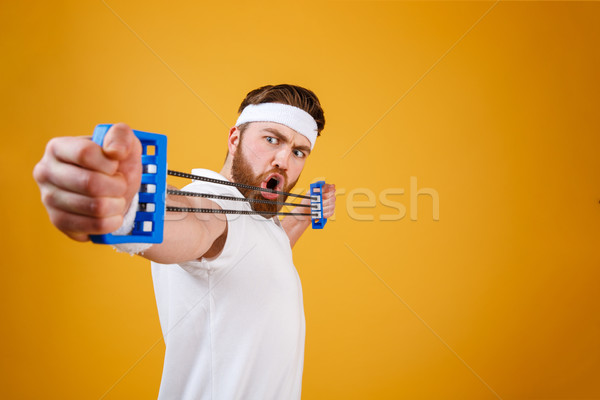 Young athletic man exercising with chest expander or resistance band Stock photo © deandrobot