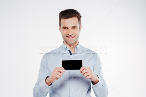 Smiling man in shirt showing blank smartphone screen Stock photo © deandrobot