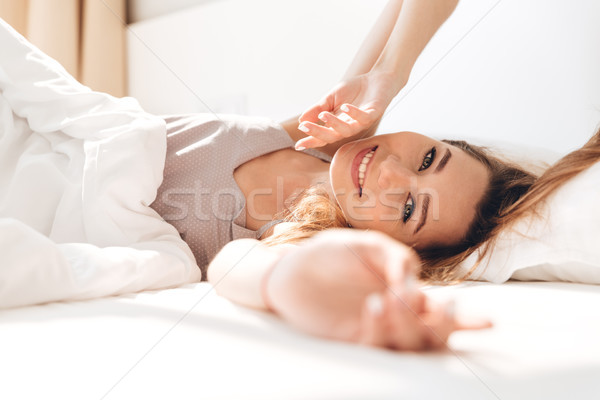 Happy pretty lady lies in bed indoors. Looking camera. Stock photo © deandrobot