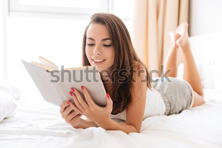 Stockfoto: Glimlachend · mooie · vrouw · lezing · boek · leggen · bed