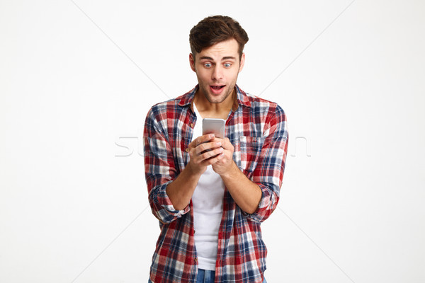 Portrait of a happy amused man looking at mobile phone Stock photo © deandrobot