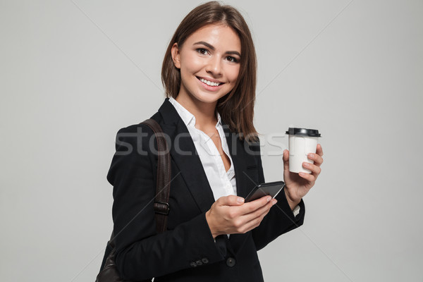 Portrait of a cheery woman in suit holding mobile phone Stock photo © deandrobot