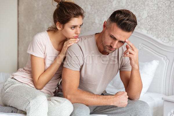 Lovely couple sitting on bed while woman calm down boyfriend Stock photo © deandrobot
