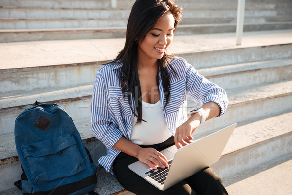 Stock photo: Close-up of cheerfull asian female student, holding laptop, chec