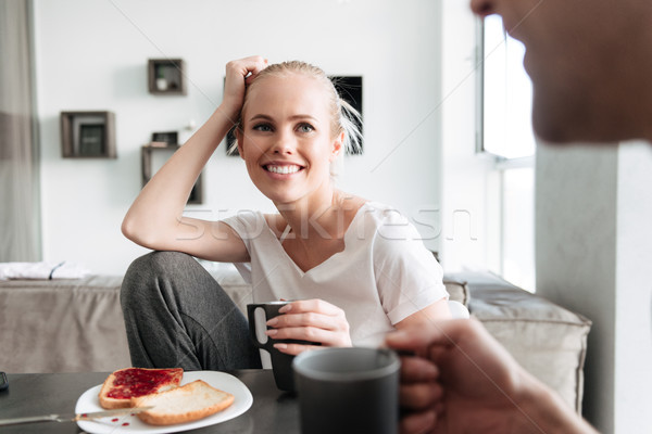Attrcative cheerful lady looking at her man while they have breakfast Stock photo © deandrobot
