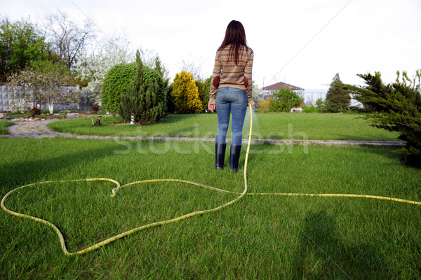 Back view portrait of a woman is watering grass in her garden Stock photo © deandrobot