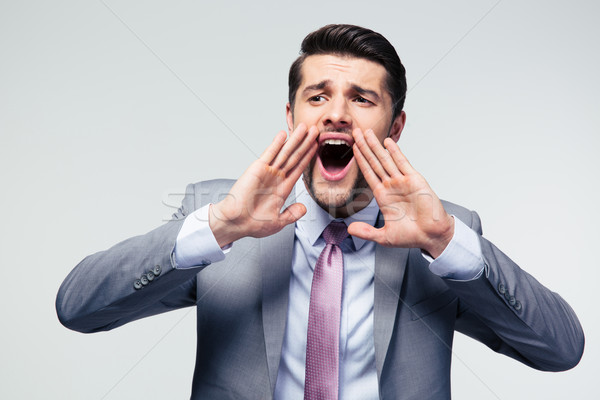 Handsome businessman shouting over gray background Stock photo © deandrobot