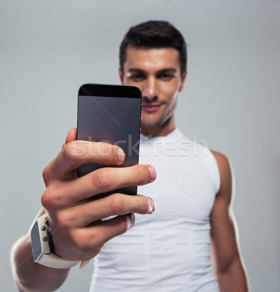 Fitness man making selfie photo on smartphone Stock photo © deandrobot