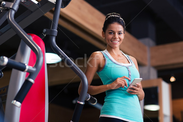 Sports woman standing with smartphone  Stock photo © deandrobot