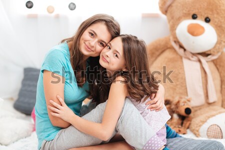 Two smiling beautiful sisters sitting together Stock photo © deandrobot
