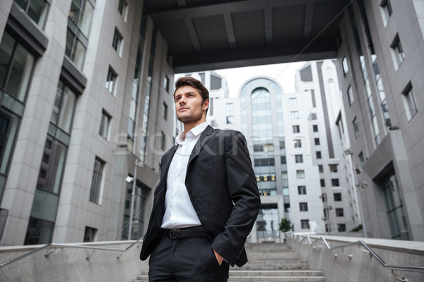 Handsome young businessman in suit standing near business center Stock photo © deandrobot