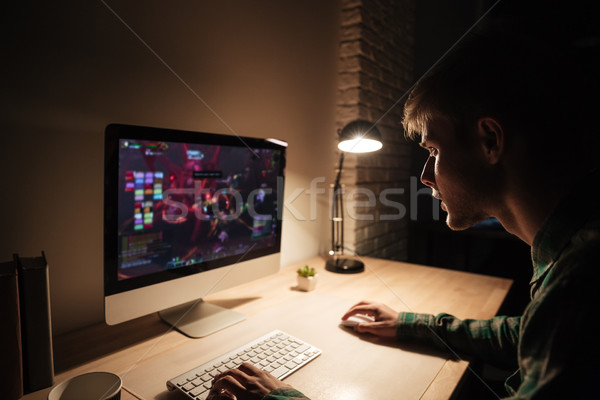 Man sitting and playing computer games in dark room Stock photo © deandrobot