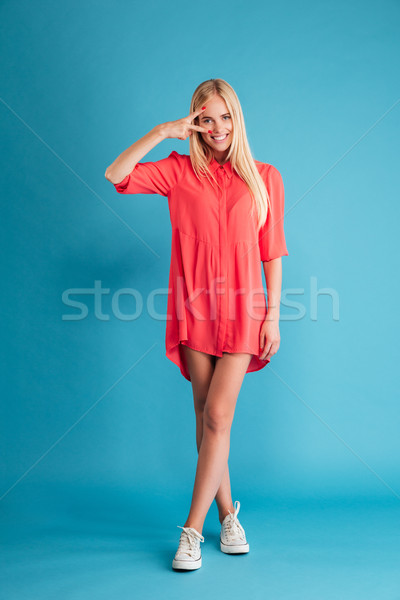 Femeie zambitoare rochie rosie în picioare victorie semna Imagine de stoc © deandrobot