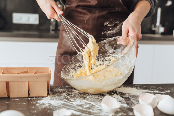 Young woman standing in kitchen and cooking Stock photo © deandrobot