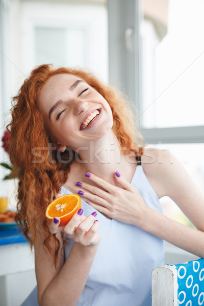 Cute cheerful young redhead lady holding orange. Eyes closed. Stock photo © deandrobot